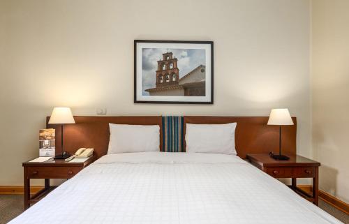 塔尔马LP Los Portales Hotel Tarma的一间卧室配有一张床、两个床头柜和两盏灯。