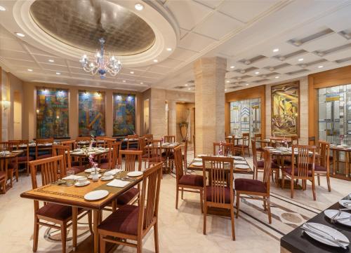 艾哈迈达巴德Sarovar Portico Kalupur Ahmedabad的餐厅设有木桌、椅子和吊灯。