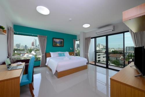 曼谷曼谷斯瑞拉哈达酒店的一间带一张床和一张书桌的卧室以及一个阳台