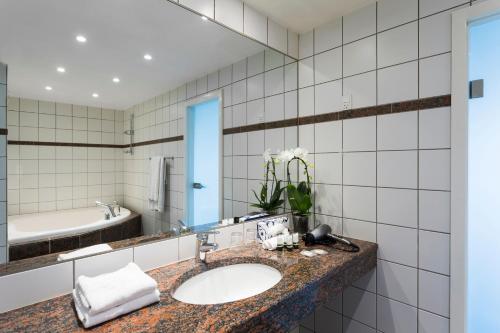 格洛斯楚普格洛斯楚普公园酒店的浴室配有盥洗盆、镜子和浴缸