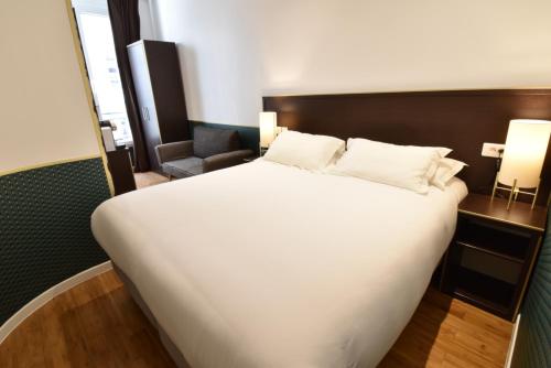 巴黎宝纳努维勒酒店的卧室配有一张白色大床和一把椅子