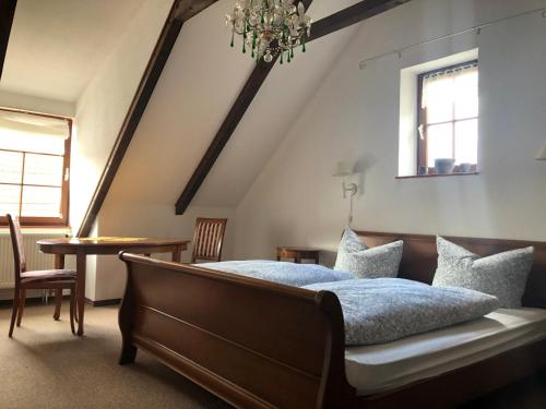 巴特贝尔卡Pension Töpferhof的一间卧室配有一张床、一张桌子和一个吊灯。