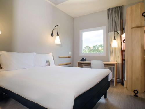 伊塔蒂巴ibis Itatiba的酒店客房设有一张白色大床和一张书桌