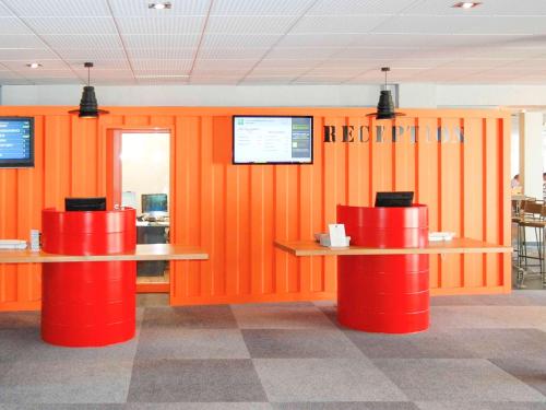 维特罗勒马赛机场宜必思尚品酒店的一间拥有橙色墙壁和两张红色桌子的餐厅