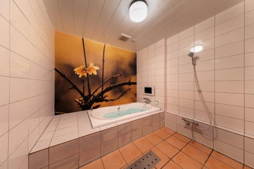 京都酒店及Spa莲花情趣酒店（仅限成人）的浴室配有浴缸,墙上挂有绘画作品