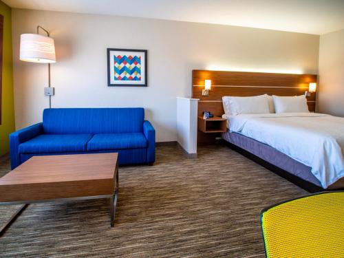 俄克拉何马城Holiday Inn Express & Suites - Oklahoma City Airport, an IHG Hotel的酒店客房,配有床和蓝色的沙发