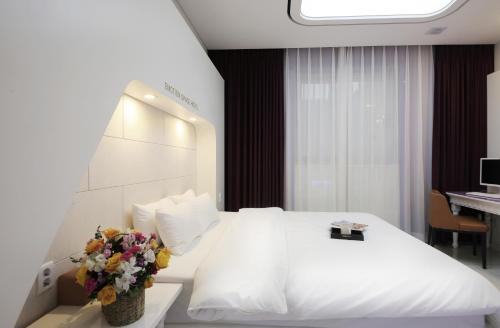 光州Urban Stay Hotel的酒店客房,配有白色的床和鲜花