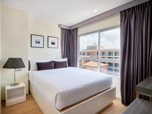 芭堤雅市中心格拉斯服务式套房酒店的一间卧室设有一张大床和一个大窗户