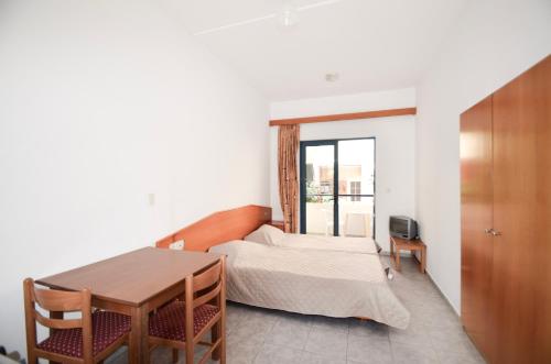 阿彻奇洛斯Stegna Star Apartments的一间卧室配有一张床、一张桌子和一个窗户。