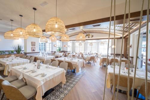 萨洛PortAventura Hotel PortAventura - Includes PortAventura Park Tickets的餐厅设有白色的桌椅和吊灯。