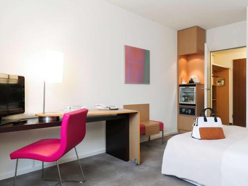 美因河畔法兰克福法兰克福诺富特酒店的酒店客房配有书桌、床、书桌和椅子。