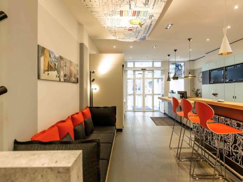 纽伦堡纽伦堡老成宜必思酒店的一间带酒吧和橙色椅子的客厅