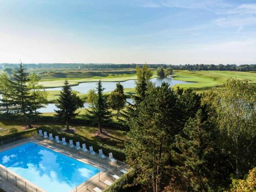 马尼·莱斯·阿莫Novotel Saint-Quentin en Yvelines的享有高尔夫球场空中美景,设有游泳池