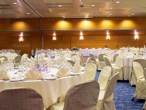 雅典雅典诺富特酒店的宴会厅配有桌椅和白色的桌布