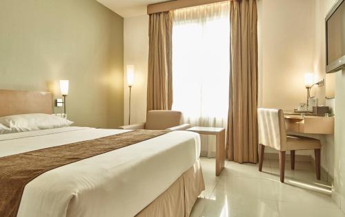 雅加达雅加达缇瑞尼缇酒店的酒店客房设有一张大床和一张书桌。