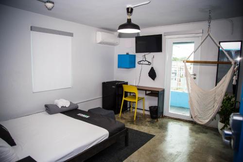 圣胡安Nomada Urban Beach Hostel- Calle Loiza的一间卧室配有一张床、一张桌子和吊床