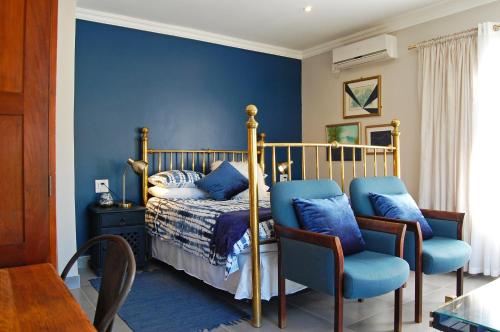 克拉伦斯Stonehaven Clarens的一间卧室配有一张蓝色墙壁的床和两把椅子