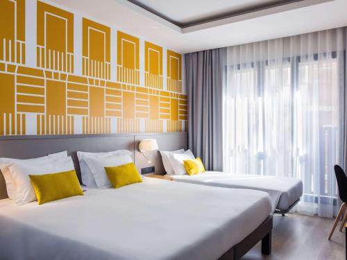 马德里Motel One Madrid-Plaza de España的黄色调的酒店客房内的两张床