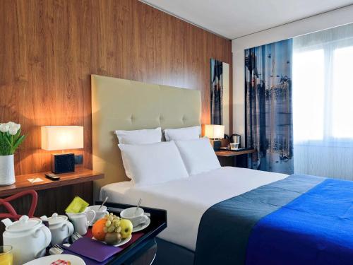 尼斯尼斯城中心圣母院美居酒店的酒店客房设有一张大床和一张带水果的桌子。