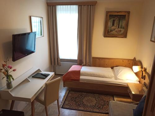 萨尔茨堡阿德霍夫酒店的一间卧室配有一张床、一张书桌和一台电视。