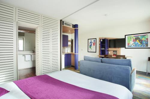 萨兰Suite-Home Orléans-Saran的一间卧室配有一张大床和紫色毯子