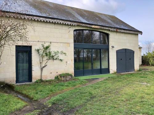 Chouzé-sur-LoireLe Logis de la Tour Saint Jacques的一座白色的建筑,有两扇门和草地庭院