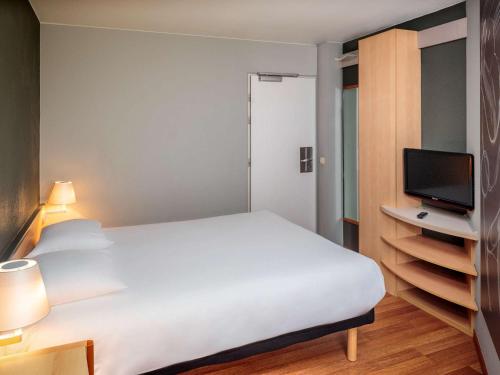 布鲁塞尔布鲁塞尔市中心宜必思酒店的卧室配有白色的床和电视。