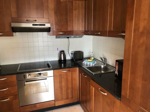 戈尔韦City Centre Apartment in Galway - 2 Bedrooms的厨房配有木制橱柜、水槽和炉灶。