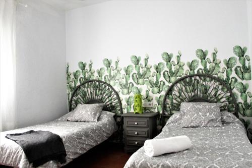 阿亚蒙特Aloja Ayamonte的一间卧室设有两张床,墙上覆盖着植物