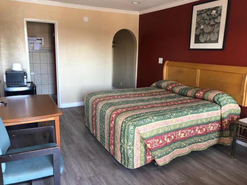 艾尔蒙特Aqua Inn Motel的配有一张床和一张书桌的酒店客房
