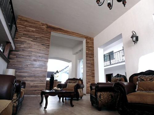 古斯曼城Hotel Hacienda的客厅配有皮革家具和砖墙