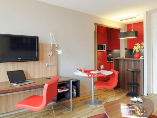 图卢兹Aparthotel Adagio Toulouse Centre Ramblas的客厅配有红色椅子和一张带笔记本电脑的桌子