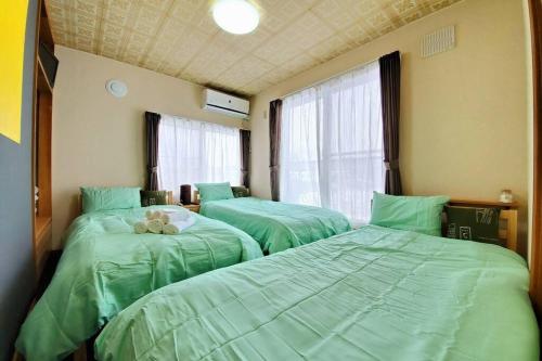 旭川旭川ファミリーハウスみんみん的带窗户的客房内的3张绿色床