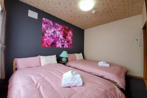 旭川旭川ファミリーハウスみんみん的卧室内配有两张粉红色的床,墙上挂着一幅画
