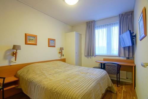 滨海卡特韦克Appartementen Zeezicht - 3的配有一张床、一张书桌和一扇窗户的酒店客房