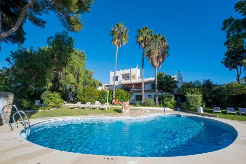 科尼尔-德拉弗龙特拉Suites Cortijo Fontanilla的一座棕榈树游泳池和一座建筑