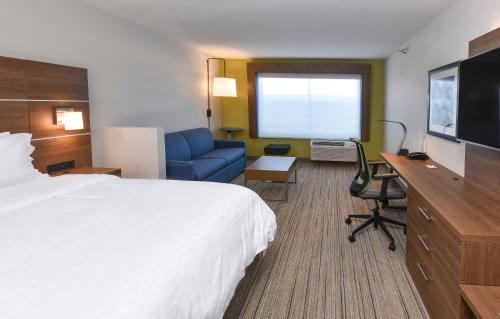 麦迪逊维尔Holiday Inn Express & Suites - Madisonville, an IHG Hotel的配有一张床和一张书桌的酒店客房