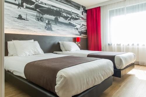霍夫多普阿姆斯特丹机场堡垒酒店的两张位于酒店客房的床,墙上挂着照片