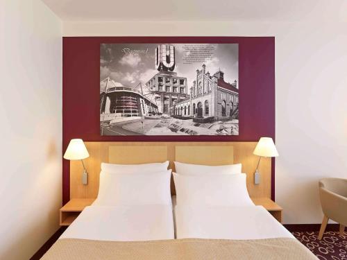 多特蒙德多特蒙得城美居酒店的一间卧室设有两张床,墙上挂着一幅画