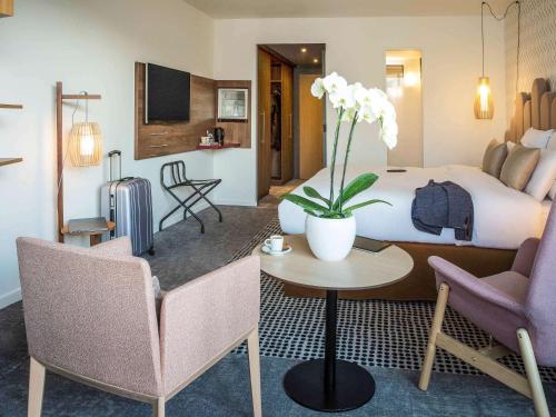 艾克斯莱班Mercure Aix-les-Bains Domaine de Marlioz Hôtel & Spa的酒店客房带一张床、一张桌子和椅子