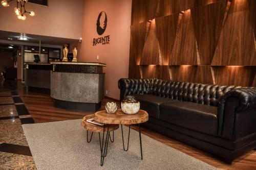 帕图布兰库Regente Hotel的客厅配有黑色真皮沙发和桌子