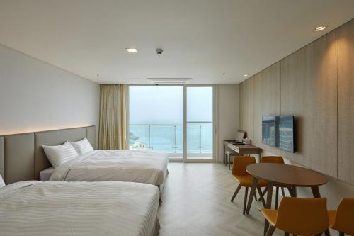 JindoSol Beach Jindo的酒店客房设有两张床、一张桌子和一张书桌。