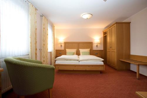 梅舍德林登霍夫酒店的一间卧室配有一张床和一把椅子