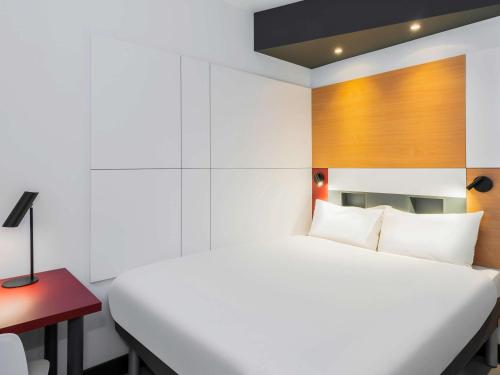奥斯坦德ibis budget Oostende Airport的卧室配有白色的床和红色的书桌