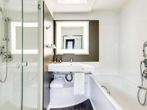 圣但尼巴黎法兰西体育场诺富特套房酒店的一间带水槽、浴缸和镜子的浴室