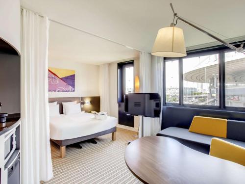 圣但尼巴黎法兰西体育场诺富特套房酒店的一间酒店客房,配有一张床和一台电视
