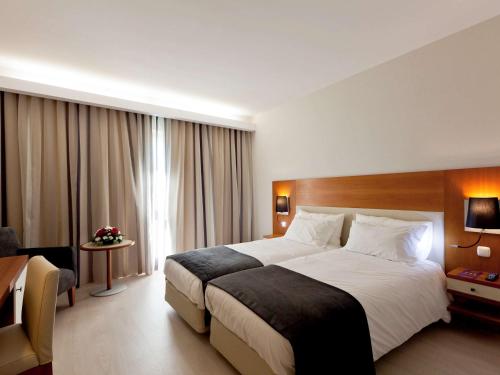 里斯本里斯本美居酒店的酒店客房设有一张大床和一张书桌。