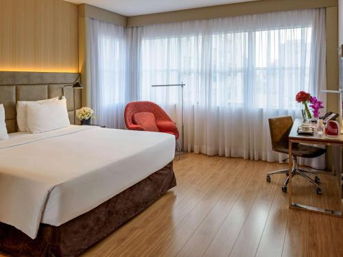 圣保罗美居圣保罗雅尔丁酒店的酒店客房设有一张大床和一张书桌。