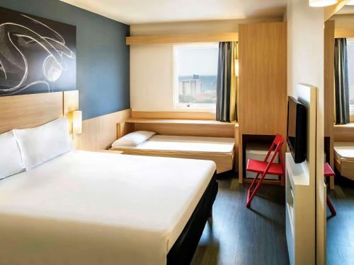 马卡埃ibis Macae的酒店客房设有两张床和电视。