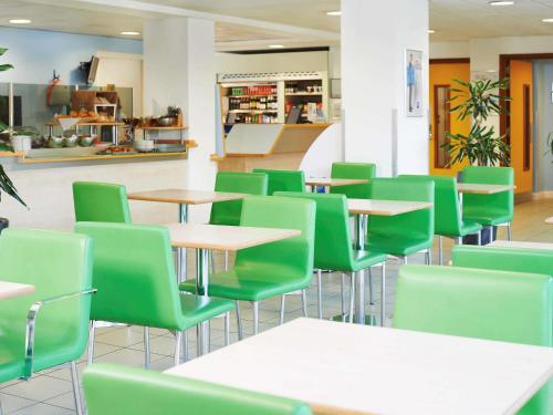 纽波特纽波特宜必思快捷酒店的一间设有桌子和绿色椅子的自助餐厅
